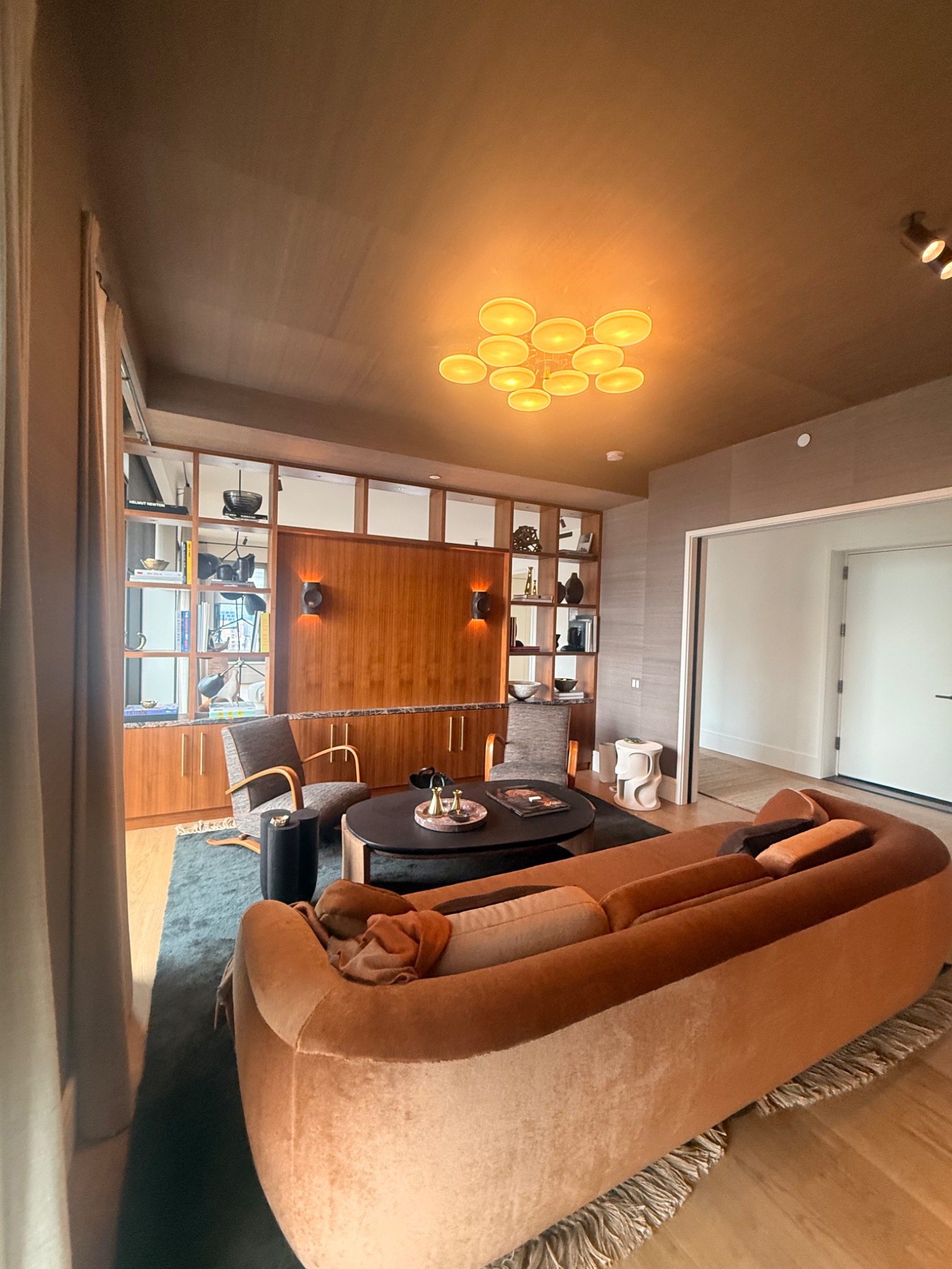 Finished living room with custom built-ins, wall lighting, and decorative ceiling fixture